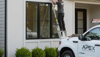 Technician repairing gray vinyl siding on Columbus OH home exterior after storm damage